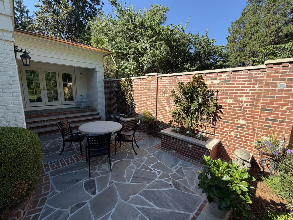 Outdoor flagstone patio with copper gutters and brick privacy wall